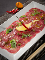 A plate of meat with a lemon wedge and a chili pepper on top