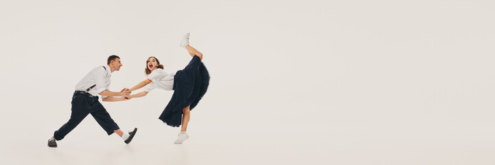 Vintage lindy hop dancers perform an energetic swing dance move in retro attire. Concept of...