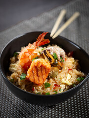 A bowl of food with shrimp, squid, and rice