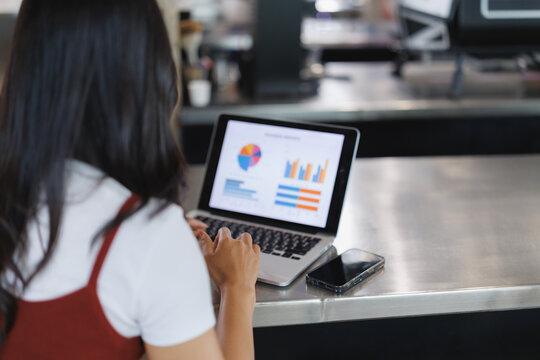 Businesswoman analyzing financial charts on laptop in coffee shop