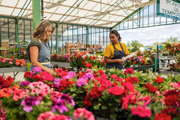Customer and employee interacting in a garden center surrounded by colorful flowers