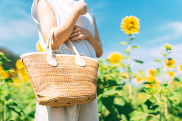 Woman standing at outdoors flower park fields hand holding fashion woven bag