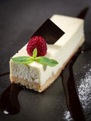 A slice of cheesecake with a raspberry on top