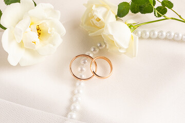 Gold wedding rings with roses and satin background