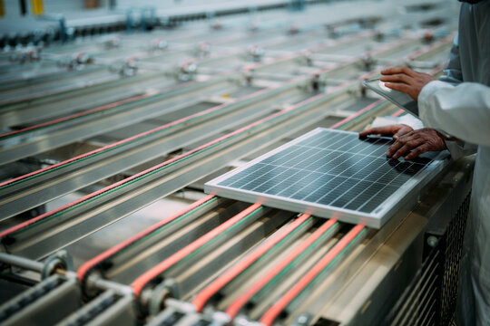 Two people inspecting a solar panel in a factory setting, focusing on renewable energy and innovation