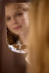 Skin-natural. Woman reflects on a rainy mirror, conveying an introspective mood. Concept of...
