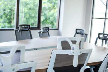 Empty Modern Conference Room With Mesh Chairs and Wooden Table Near Large Windows