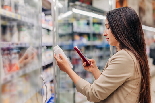 Woman using mobile application to scan products in the dairy section of a supermarket