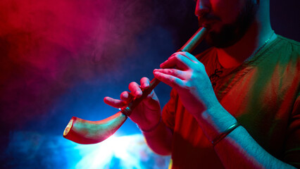 A man plays a horn instrument, enveloped by colorful smoke. Concept of music's lively expression...