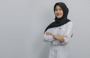 
A confident Muslim woman wearing a black hijab and white shirt poses with her arms crossed on a...