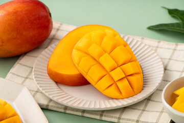 Fototapeta premium Fresh ripe mango with cubes on green table background.