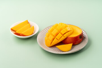 Fresh ripe mango with cubes on green table background.