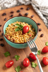 Homemade couscous salad with fresh cherry tomatoes served on a bowl.