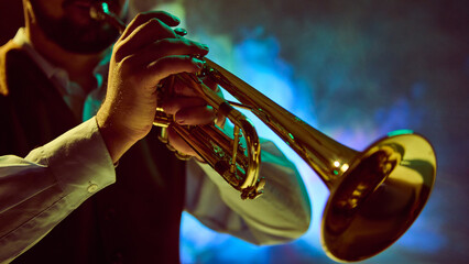 A musician skillfully plays the trumpet on stage with vibrant lighting creating a dynamic backdrop....