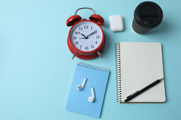 blank notepad with clock, alarm clock and pen on blue pastel pink background.