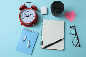 blank notepad with clock, alarm clock and pen on blue pastel pink background.