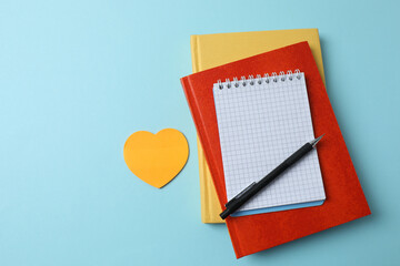 blank notepad with clock, alarm clock and pen on blue pastel pink background.