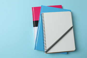 blank notepad with clock, alarm clock and pen on blue pastel pink background.