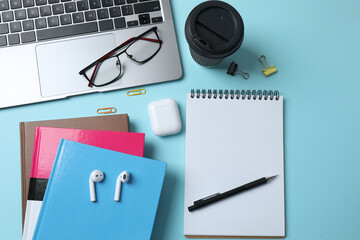 laptop glasses coffee headphones notepad on a blue background with space for text