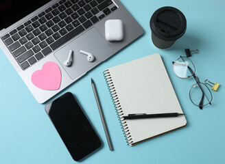 laptop glasses coffee headphones notepad on a blue background with space for text