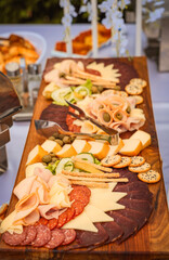 Gourmet charcuterie board with assorted meats, cheeses, olives, and crackers arranged on a wooden platter for an elegant outdoor event or wedding reception.