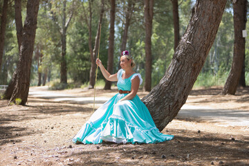 Young, beautiful, blonde woman wearing a typical Andalusian flamenco dress in light blue for going...