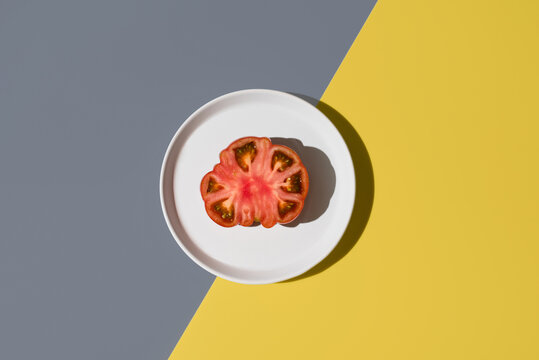Sliced raf tomato with salt on a white plate from top view