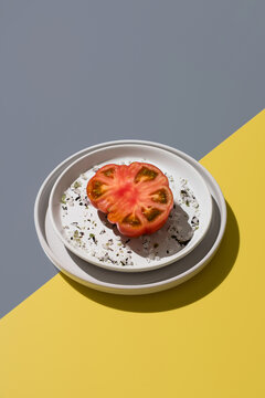 Raf tomato with salt and spices on plate, yellow and gay background
