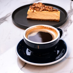 Mocha black coffee with hazelnut cheesecake slice on marble table