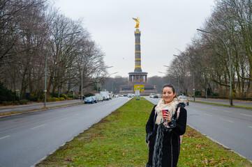 Woman with coffee in front of Berlin Victory Column.