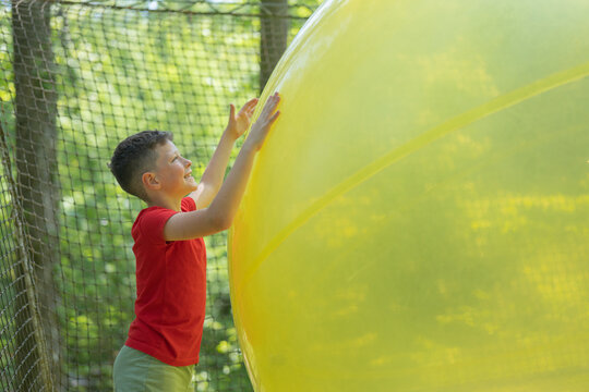Boy enjoying giant yellow ball in adventure park