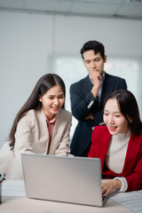 Group of young asian businesspeople working together using laptop in office meeting. Teamwork concept. Happy smiling young asian businesspeople working together using laptop computer in office meeting