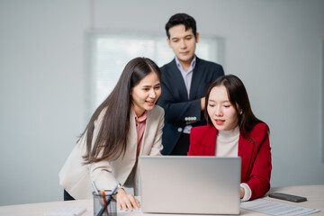 Asian businesspeople discussing and working together using laptop computer in modern office,...