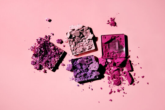 Top view of vibrant eye shadow palettes on pink surface