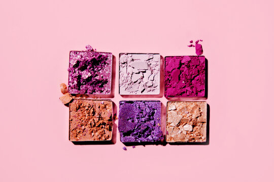 Top view of colorful eye shadows on pink background