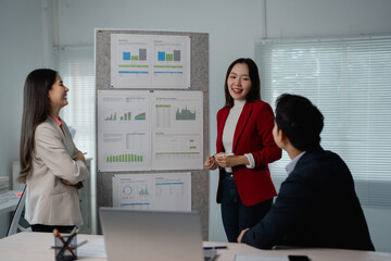 Group of asian businesspeople are discussing company performance, looking at charts and graphs...