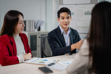 Young confident asian businessman leading a meeting with colleagues, discussing company strategy and analyzing financial data in modern office boardroom