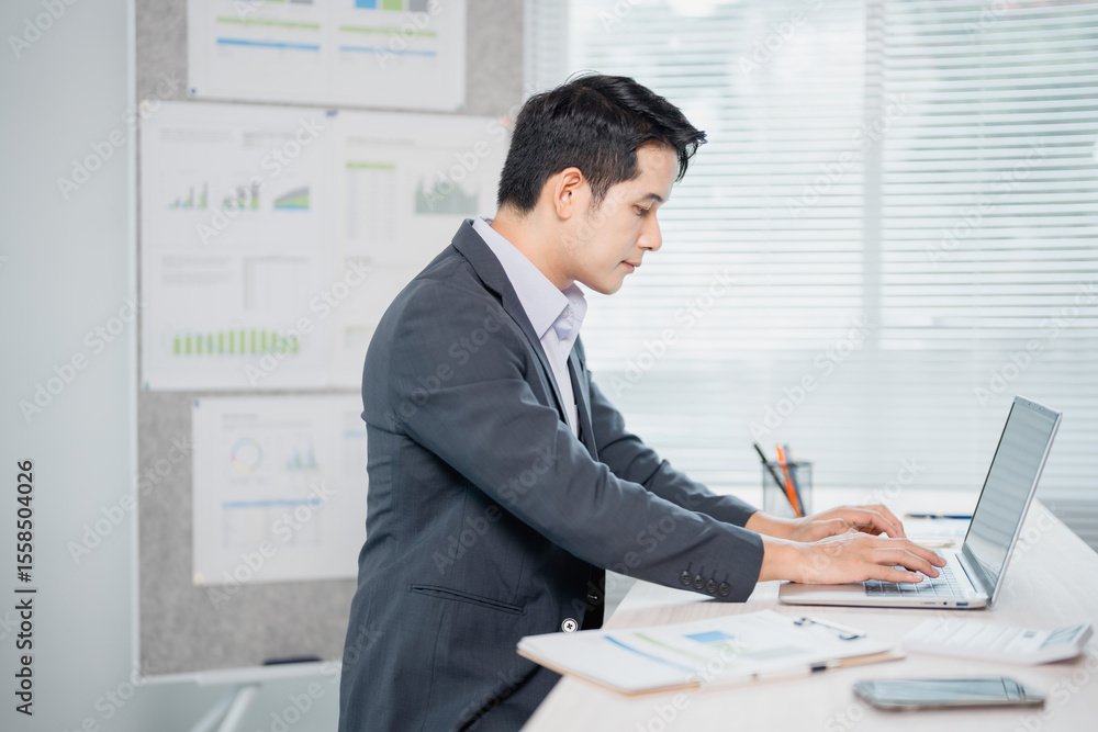 Poster young professional working at a bright, modern desk, using a laptop to analyze data and prepare repo
