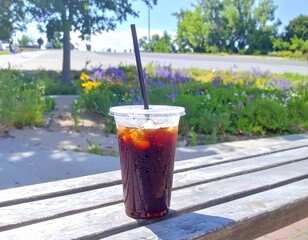 野外のベンチの上のテイクアウトのアイスコーヒー