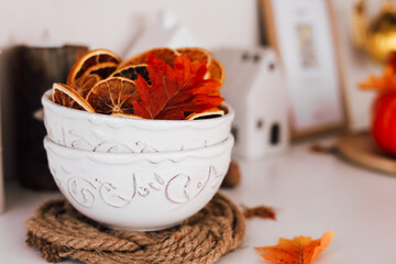 Decorative bowls with dried orange slices and autumn leaves on a rustic cozy table