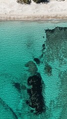 Vue verticale de la plage de Saint Cyprien en Corse, r&eacute;v&eacute;lant le sable blanc, l&rsquo;eau turquoise et les fonds marins sombres.