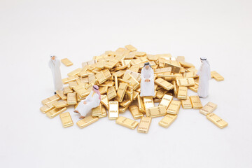 Miniature Figures Standing Around Pile of Shiny Gold Bars