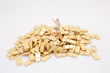Miniature Figure on a Pile of Gold Bars Representing Wealth and Prosperity