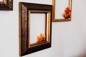 Decorative empty frames with colorful leaves displayed on a white wall in an indoor setting