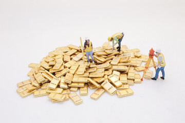 Miniature Workers Analyzing a Heap of Gold Bars