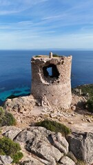 Tour g&eacute;noise de Roccapina en Corse, b&acirc;tie en pierre sur un promontoire rocheux, surplombant la mer M&eacute;diterran&eacute;e aux eaux limpides.