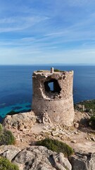 Tour g&eacute;noise de Roccapina en Corse, b&acirc;tie en pierre sur un promontoire rocheux, surplombant la mer M&eacute;diterran&eacute;e aux eaux limpides.