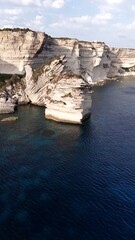 Falaises blanches et grain de sable de Bonifacio plongeant dans la mer m&eacute;diterran&eacute;en, photographi&eacute;es en hauteur par une lumi&egrave;re de fin d&rsquo;apr&egrave;s-midi.