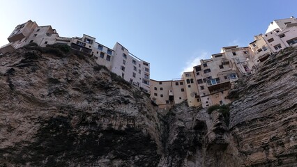 Maisons de Bonifacio construites au bord des falaises calcaires, vue depuis le bas montrant la hauteur et les d&eacute;tails architecturaux.