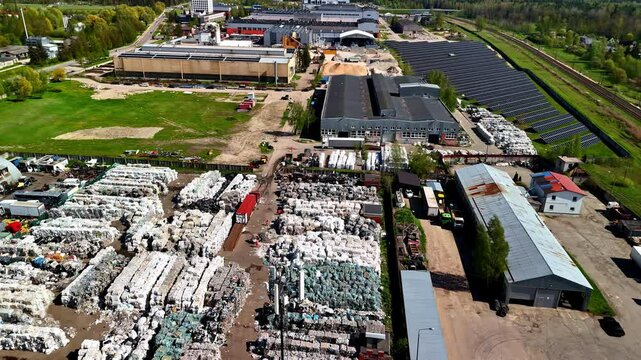 Landfill waste site with trash compactors beside solar panels, aerial view from above